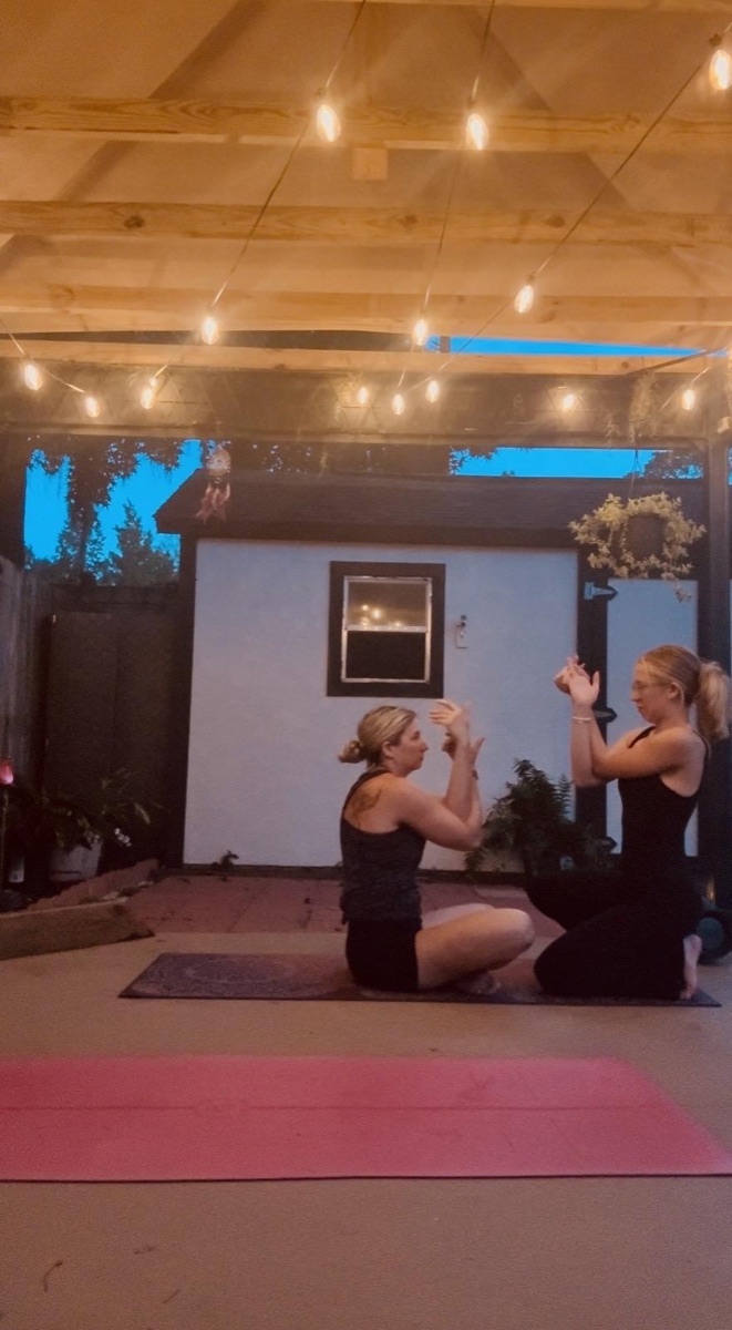 Partner yoga under warm string lights