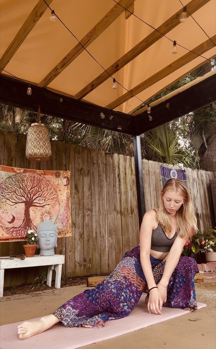 Seated practice beside a tapestry and Buddha