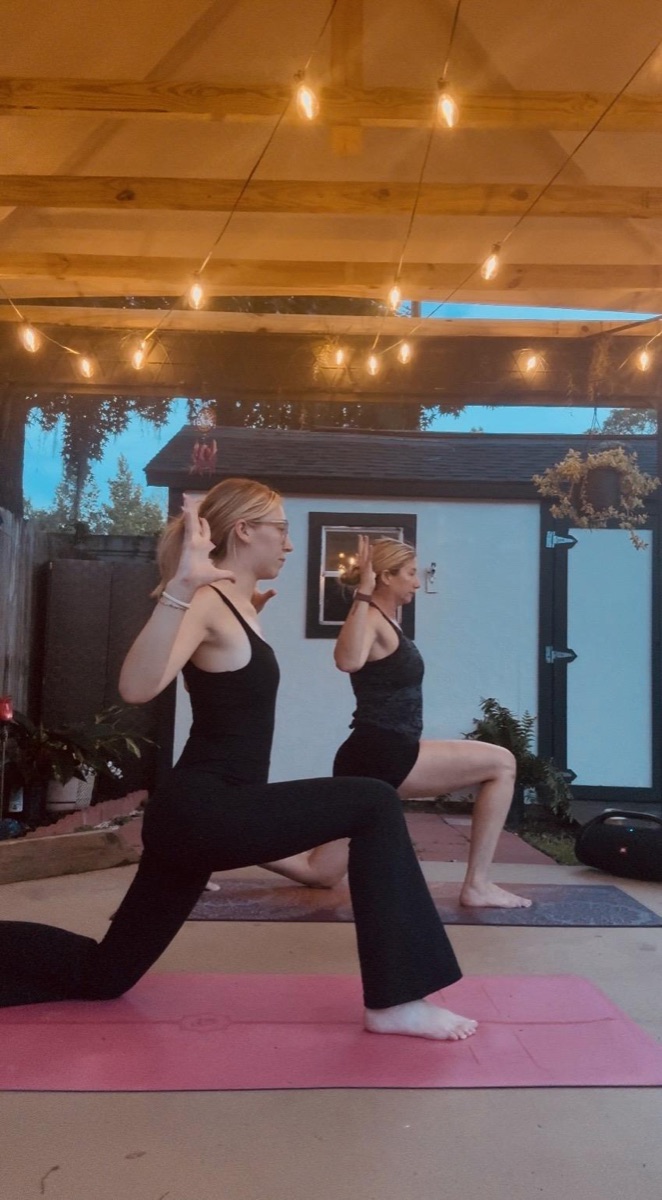 Two people practicing yoga together under string lights